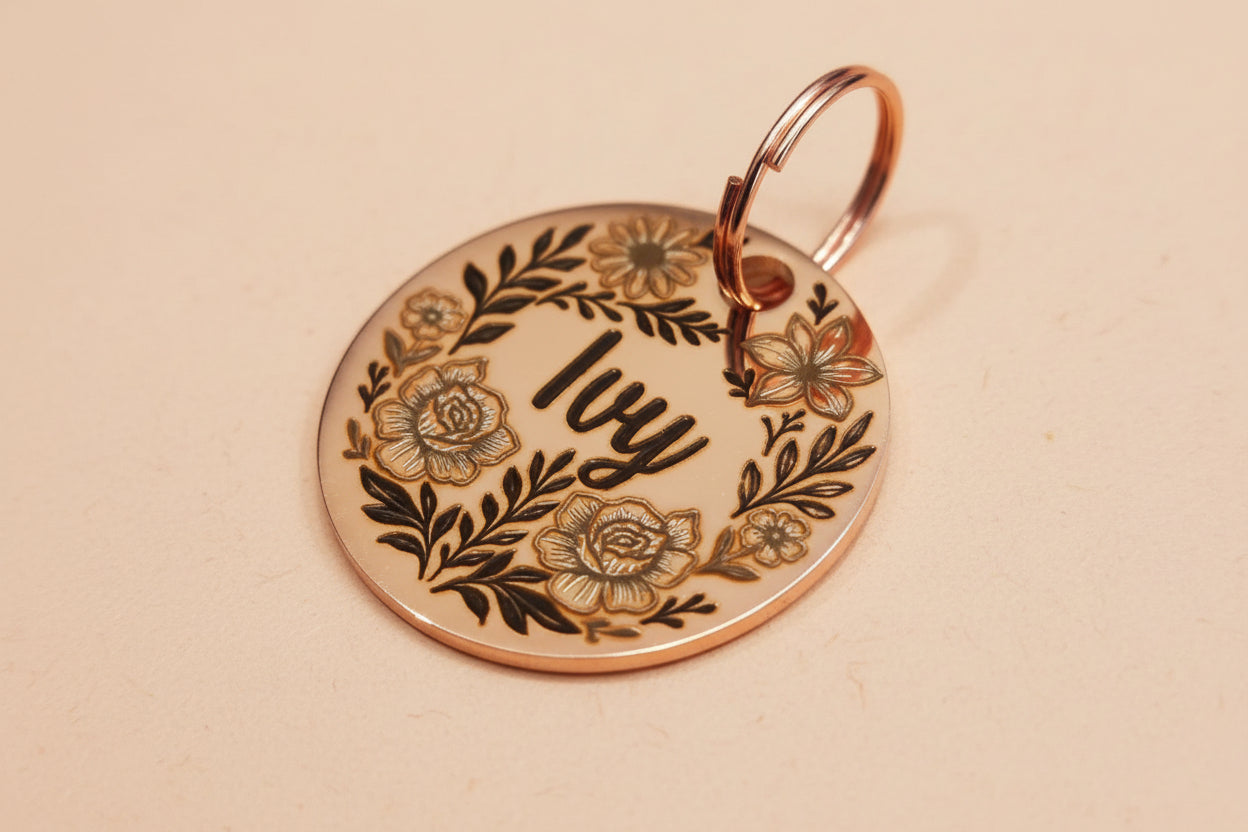 Round metallic dog tag with floral designs and 'Ivy' engraved of the surface