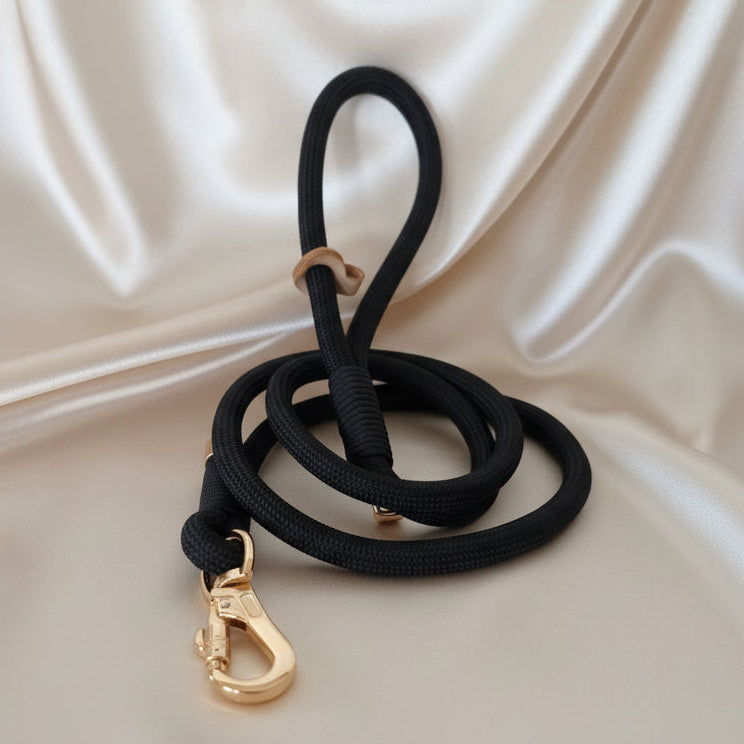 Black rope dog leash with gold clasp on a white wedding satin background