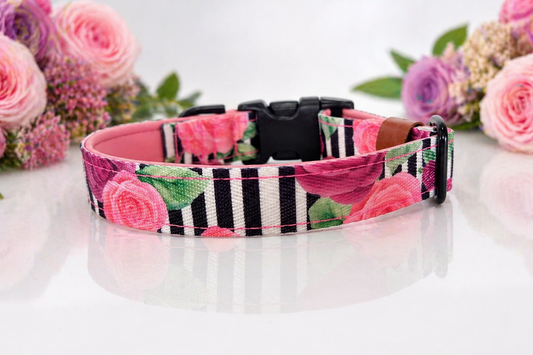Floral patterned dog collar on a white surface with pink flowers in the background