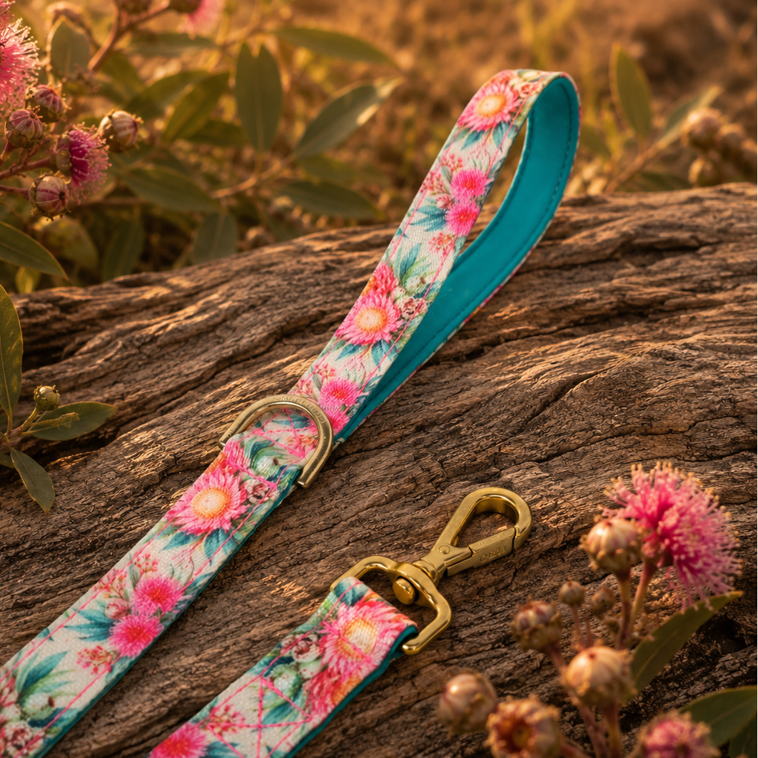Floral-patterned dog leash on a wooden log with pink flowers in the background