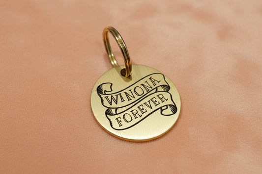 Gold dog tag with name engraved in a ribbon