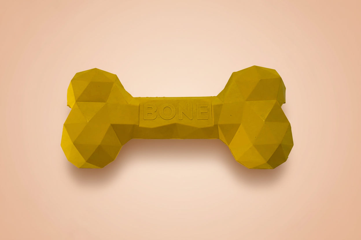 A bright yellow low-poly dog toy shaped like a bone, with the word 'BONE' embossed in the center